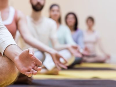 Group of people doing meditation on exercise mat in the fitness studio